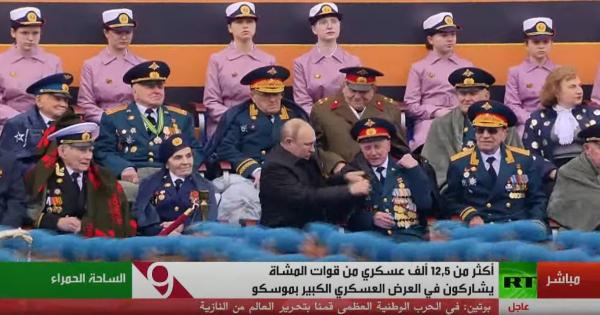 بوتين يساعد أحد المحاربين في ارتداء المعطف أثناء العرض العسكري في الساحة الحمراء
